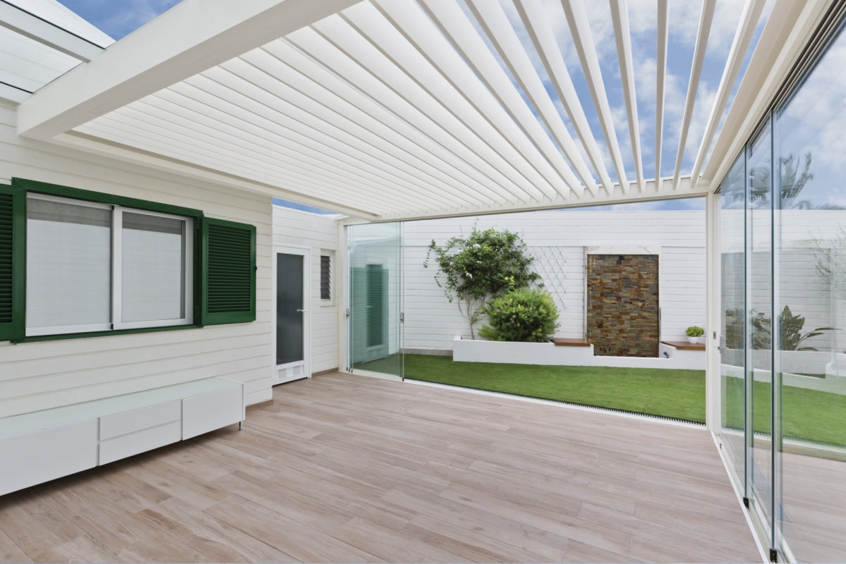 Glazen terraswand onder een lamellenpergola